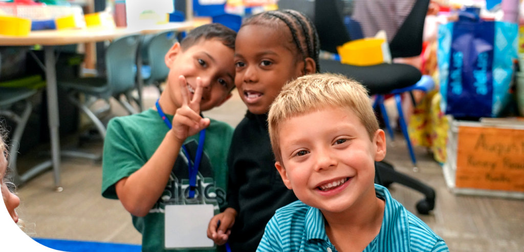 Children smiling and posing happily in a classroom setting.