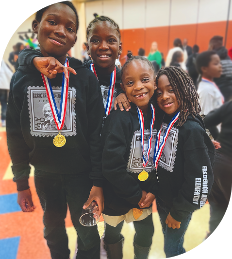 Children wearing medals and matching sweatshirts smile indoors at an event.